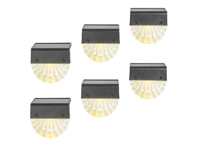 Zes op zonne-energie werkende LED-wandlampen met geribbelde, waaiervormige diffusers.