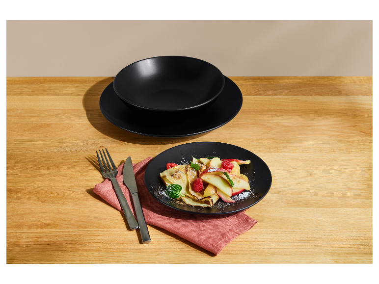 Zwarte keramische serviesset met een heerlijk dessert op een houten tafel.