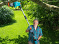 Man gebruikt een Gardena telescopische takkenzaag in de tuin.