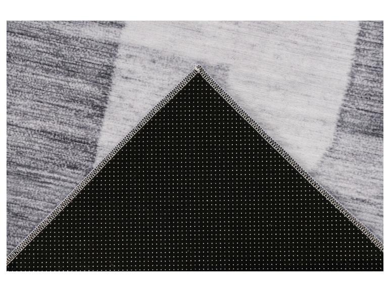 Grijs vloerkleed met streepmotief en antislip onderkant met witte stippen.