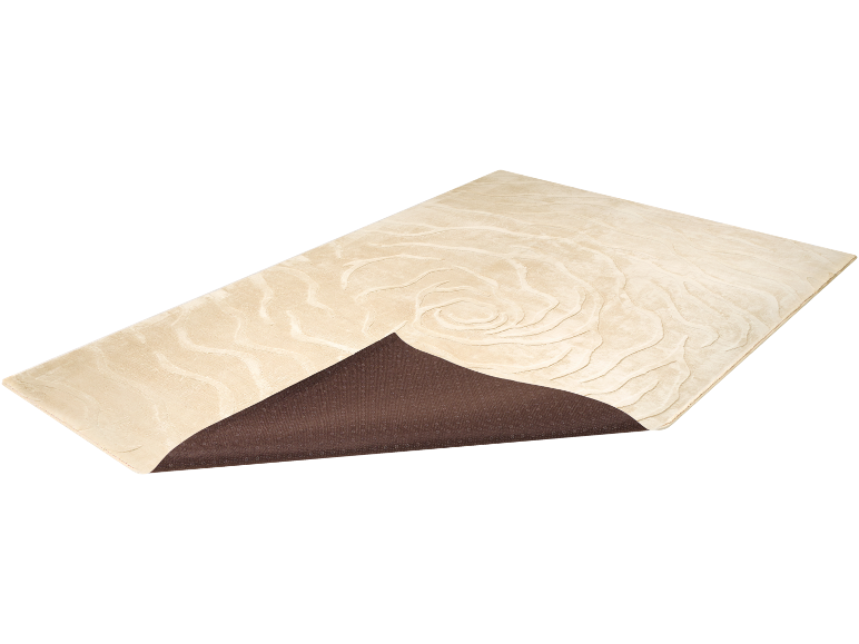 Beige vloerkleed met abstract patroon en gedeeltelijk zichtbare bruine antislip onderkant.