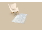Beige fauteuil met een lichtblauw vloerkleed op een beige achtergrond.