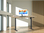 Een houten bureau met een elektrisch verstelbaar onderstel en een computermonitor.