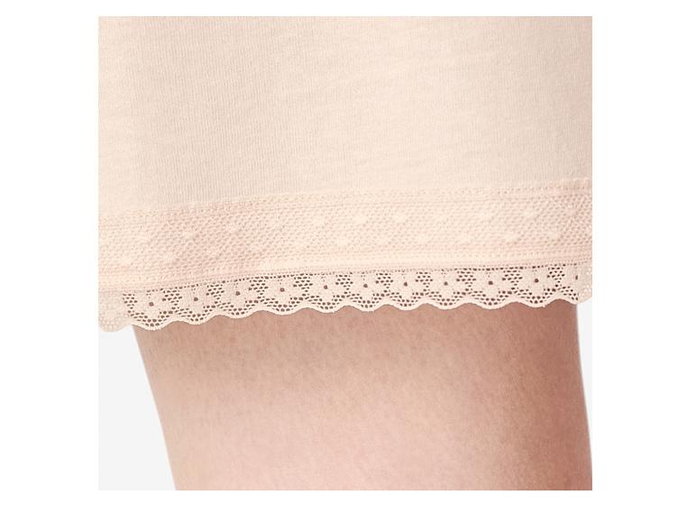 Close-up van een vrouwenbeen met een lichtroze short met kanten rand.