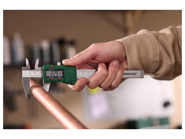 Een persoon meet een koperen pijp met een PARKSIDE digitale schuifmaat.