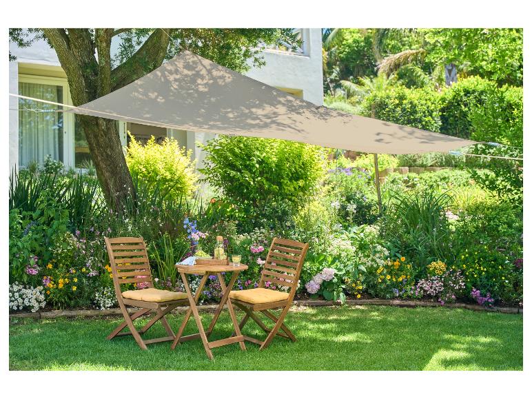 Beige parasol en houten tuinmeubelen in een bloeiende tuin.