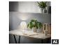 Witte tafellamp op een houten bureau met planten en boeken.