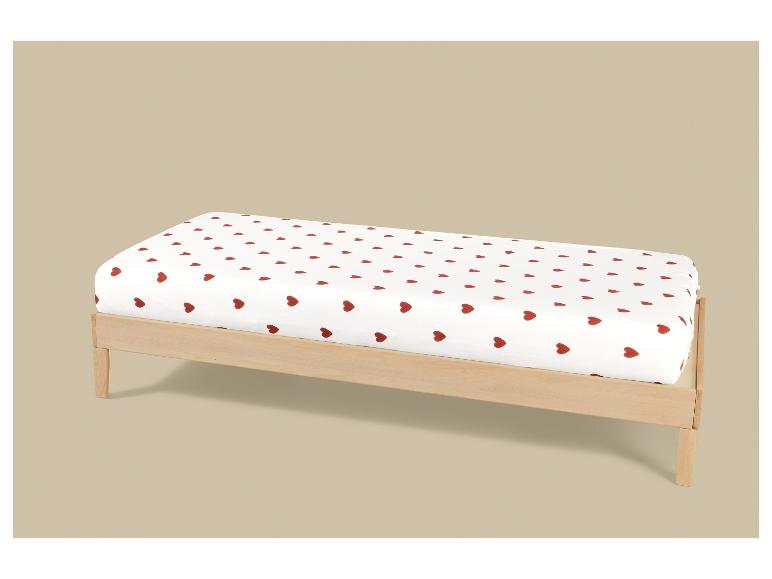 Kinderbed met een wit hoeslaken met rode hartjes.