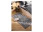 Grijs vloerkleed met geometrisch patroon in slaapkamer met houten vloer en bed.