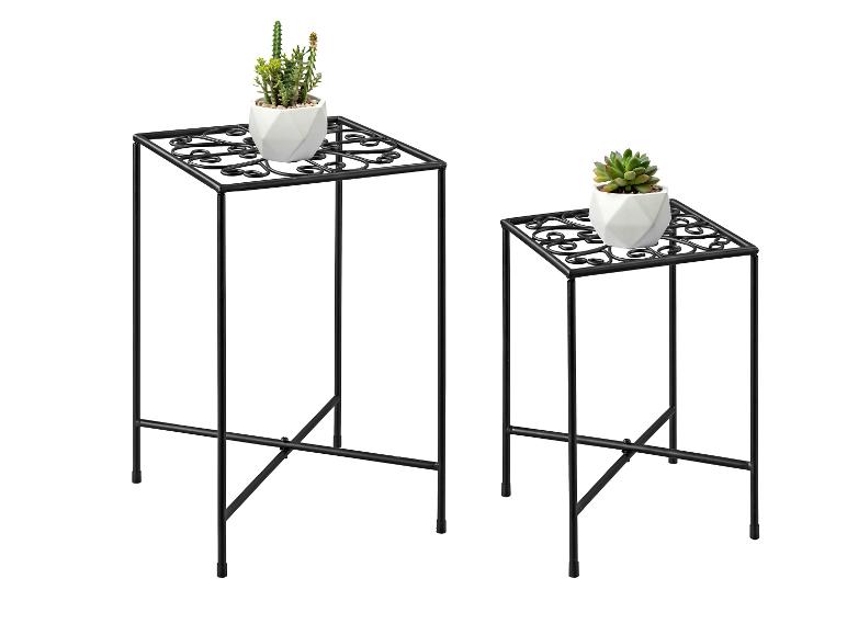 Twee zwarte metalen plantenstandaards met decoratieve patronen, elk met een vetplant.