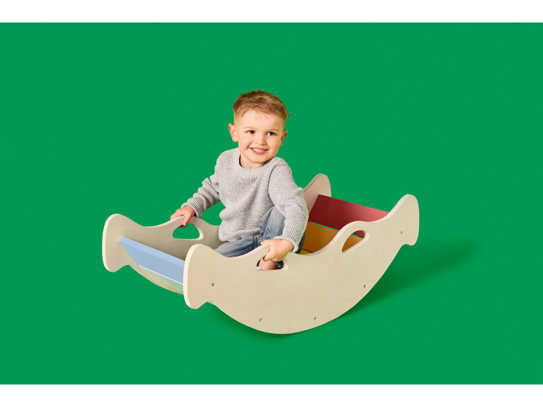 Lachende jongen zit in een houten schommel met kleurrijke accenten.