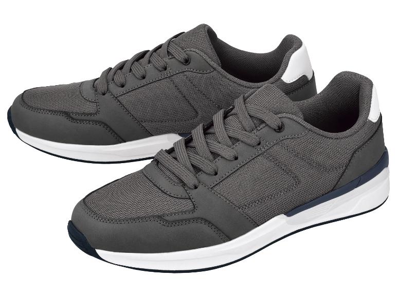 Paar grijze herensneakers met witte en donkerblauwe zolen.