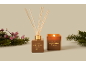 Geurstokjes en kaars met Marshmallow Fireside-geur, omringd door dennentakken en bessen.