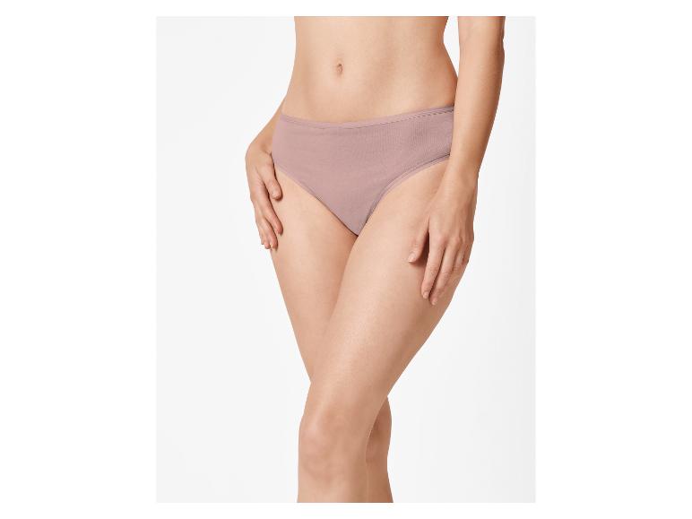 Vrouw in beige slip, met handen op de heupen.