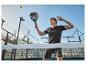 Man in zwarte sportkleding speelt padel met racket en bal.