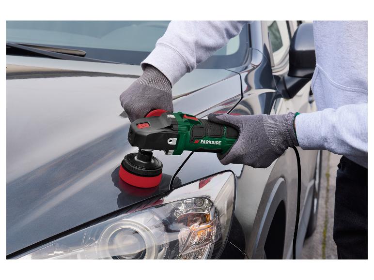 Man polijst de motorkap van een grijze auto met een elektrische polijstmachine.