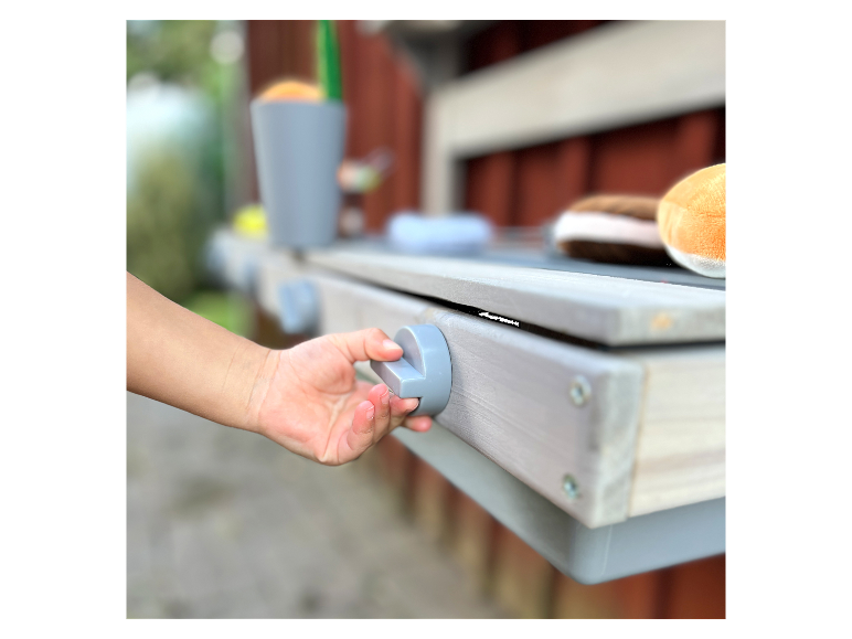 Een kind speelt met een grijze houten speeltafel.