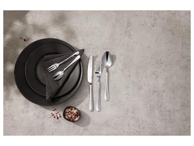Bestekset met zwarte borden en een kom kruiden op een betonnen ondergrond
