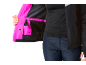 Vrouw in zwarte jas met roze voering en donkerblauwe broek.