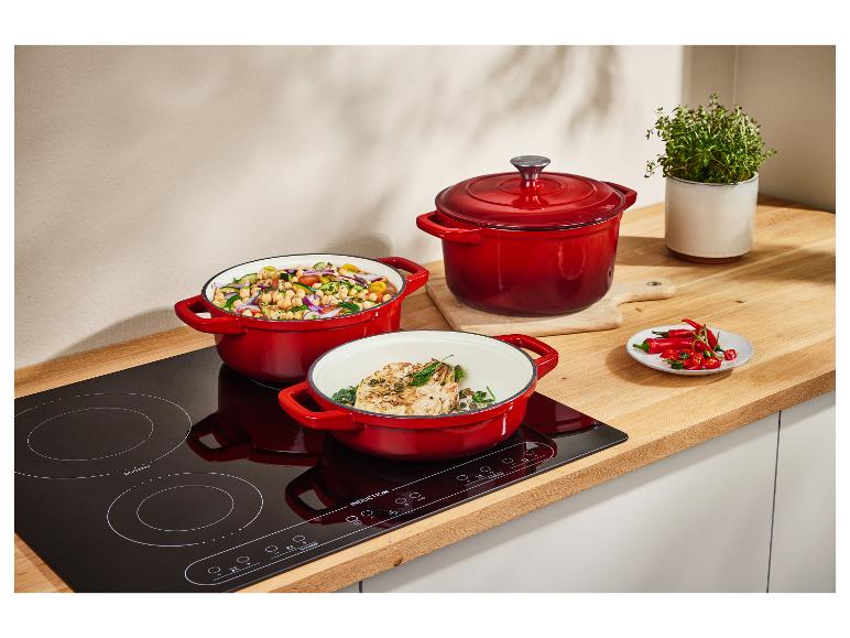Drie rode Le Creuset pannen op een inductiekookplaat.