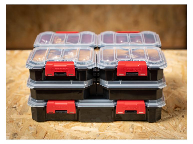Vier gestapelde opbergdozen met transparante deksels en rode sluitingen op een houten ondergrond.