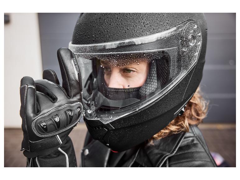Persoon in zwarte motorhelm met waterdruppels en zwarte handschoen met 'VISOR WIPE' tekst.
