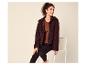 Vrouw in een bruine teddy fleece jas, bruine top en zwarte legging, zittend op een stoel.