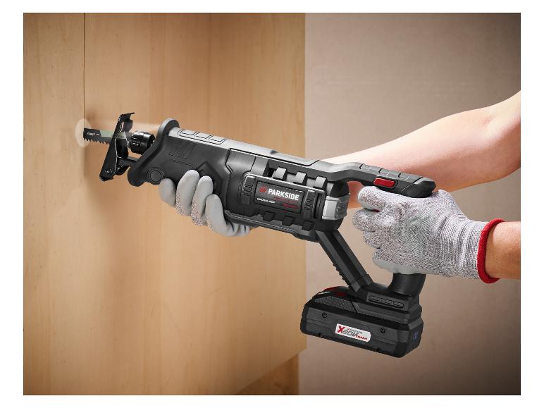 Een persoon gebruikt een draadloze reciprozaag om een gat in een houten muur te zagen.