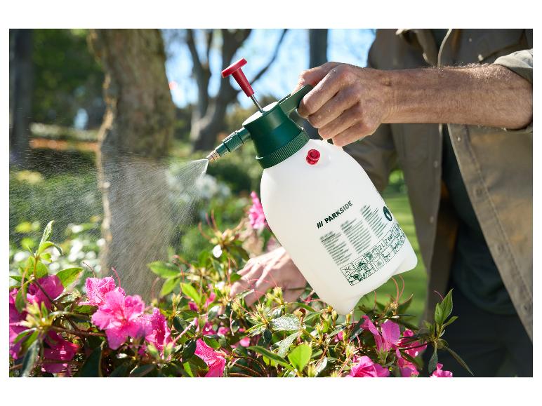 Man besproeit roze bloemen met een Parkside sproeier