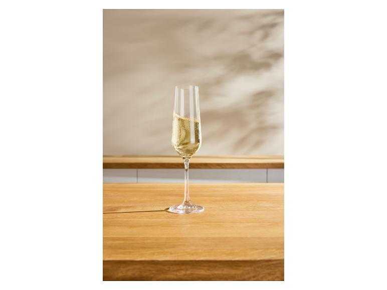 Een flûteglas gevuld met mousserende wijn op een houten aanrecht.