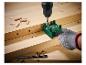 Boormachine en groene boormal die een houten plank boort, met deuvels en boren