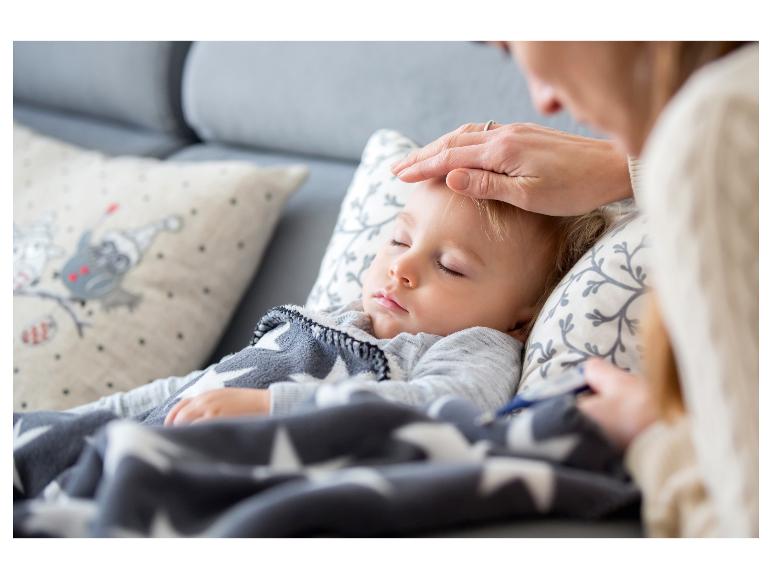 Moeder controleert temperatuur slapende baby met sterrendeken.
