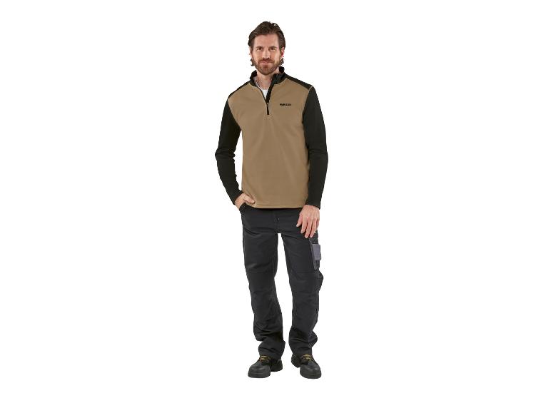 Man draagt een Parkside beige en zwarte trui en een zwarte werkbroek.