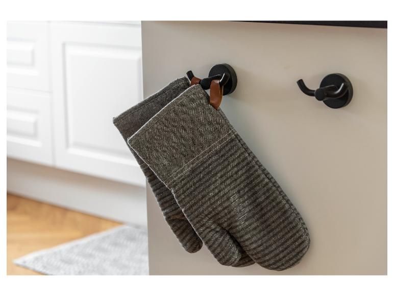 Twee grijze, gestreepte ovenwanten hangen aan een keukenhaak.