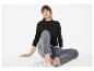 Vrouw in zwart shirt met lange mouwen en grijze jeans, zittend op de grond