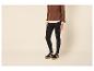 Vrouw in bruine trui, wit overhemd, zwarte legging en sneakers.