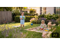 Kinderen spelen in de tuin: jongen met waterpistool, meisje in zandbak.