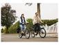 Twee mensen fietsen op elektrische fietsen op straat, een vrouw op een lichte en een man op een donkere fiets.