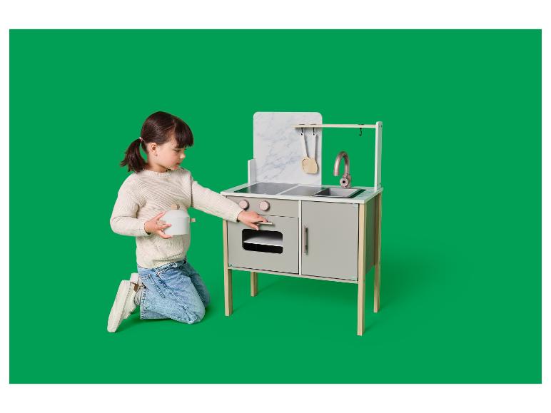 Een meisje speelt met een grijs-witte speelkeuken met een gemarmerde achtergrond.