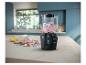 Blender met doorsnede, toont intern mechanisme, met roze smoothie en fruit op tafel.