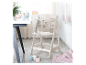 Lichtbeige houten Stokke Tripp Trapp kinderstoel met babyaccessoires.