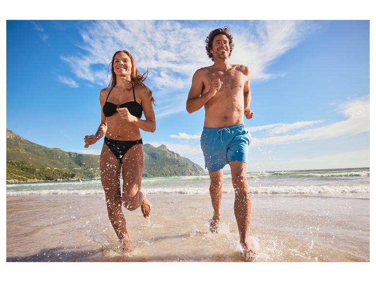Koppel rent op het strand in badkleding.