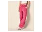 Vrouw in fuchsia wijde broek en een witte crop top, met witte sneakers.