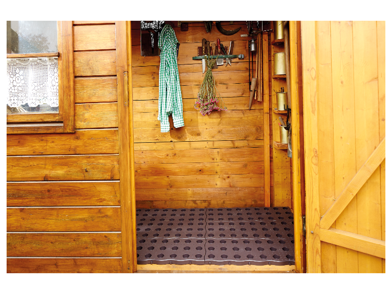 Houten tuinberging met gereedschap, vloermat en kleding.