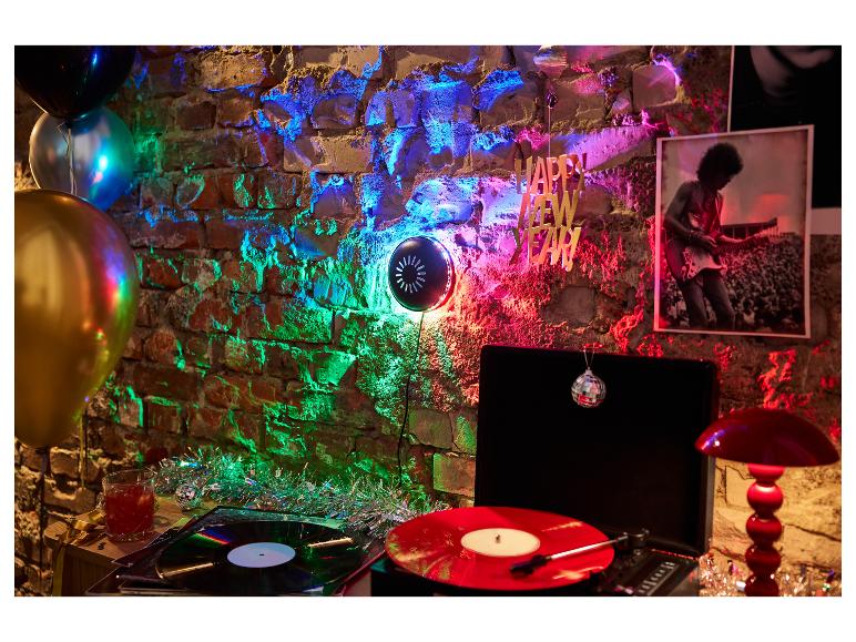 Nieuwjaarsfeest met platenspeler, ballonnen en kleurrijke verlichting op een bakstenen muur.