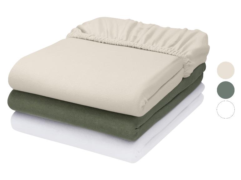 Stapel van drie hoeslakens in beige, groen en wit met kleurstalen.