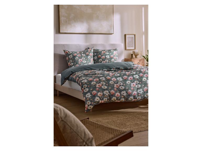 Slaapkamer met een bed met bloemendekbedovertrek en kussens, een nachtkastje en wanddecoratie.