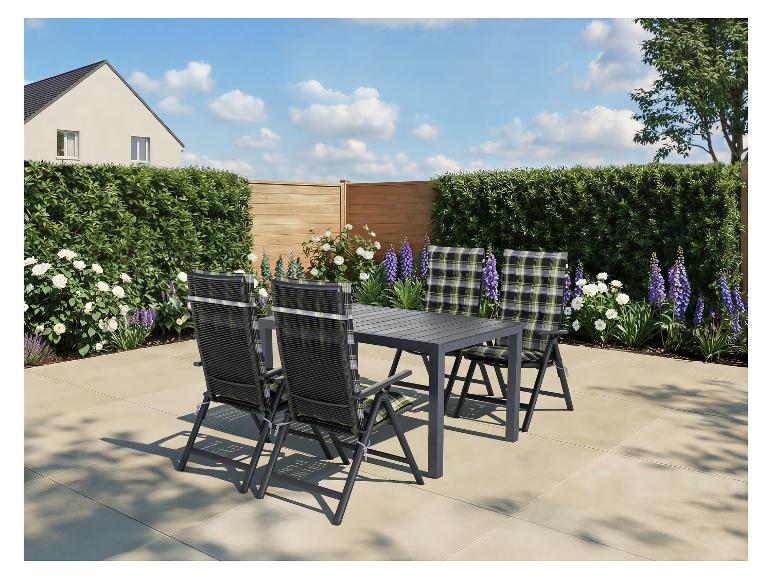 Terras eethoek met grijze tafel en vier stoelen met geruite kussens in een tuin.