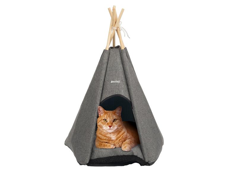 Rode kat rustend in een grijze tipi-huisdierenmand met houten stokken.