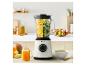 Blender met fruit en groenten, naast een glas sap en een kom soep.